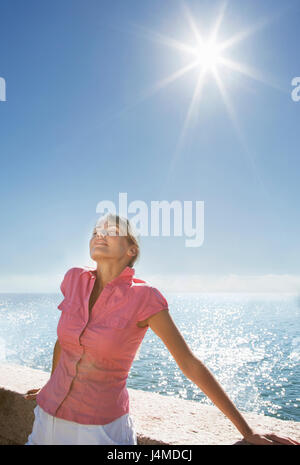 Caucasian woman se dorer sous le soleil près de ocean Banque D'Images