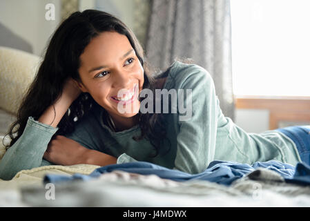 Smiling Hispanic woman laying on bed Banque D'Images