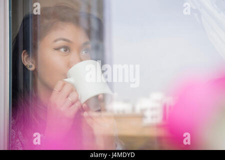 Mixed Race woman drinking coffee derrière Banque D'Images