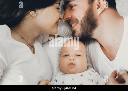 Mère et père de race blanche portant sur le lit avec son bébé Banque D'Images