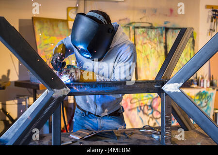 Caucasian man welding metal sculpture Banque D'Images