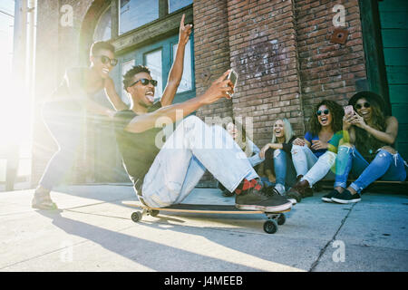 Ami Woman sitting on skateboard en ville Banque D'Images