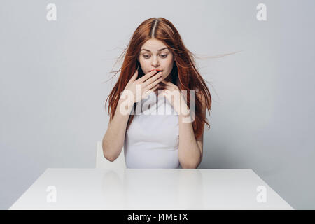 Surpris Caucasian woman sitting at table venteux Banque D'Images