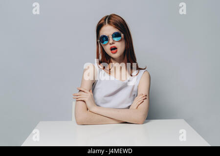 Caucasian woman sitting at table with attitude portant des lunettes de soleil Banque D'Images