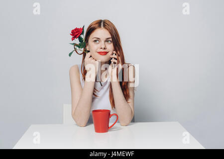 Caucasian woman holding rose talking on cell phone Banque D'Images