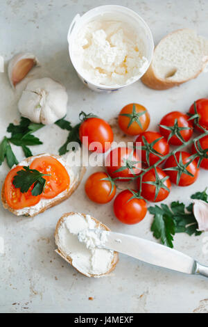 Les tomates de vigne près de pain et de fromage à la crème Banque D'Images