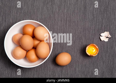 Oeufs dans une assiette blanche, l'un à côté de l'oeuf entier oeuf cassé sur la table Banque D'Images