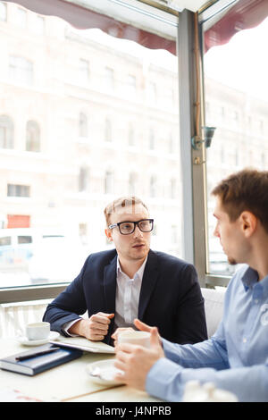 Portrait of young man wearing grands verres consulting à table in cafe Banque D'Images