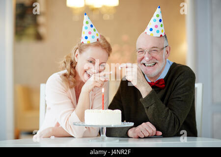 Rire les aînés en s'amusant avec des bouchons d'anniversaire cake Banque D'Images