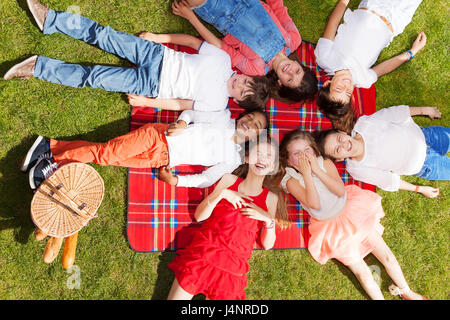 Vue de dessus portrait de sept enfants rire pose en un cercle sur la couverture de pique-nique sur la main panier en été Banque D'Images