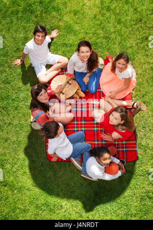 Vue de dessus portrait de sept amis heureux de vous détendre sur une couverture de pique-nique près d'un panier sur un pré herbeux Banque D'Images