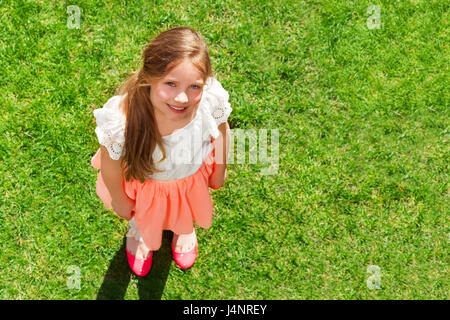 Top View portrait of smiling 10 ans, fille, debout sur la pelouse d'été vert Banque D'Images
