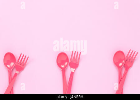 Vue supérieure de la fourchette et cuillère en plastique de couleur rose sur fond de table avec l'exemplaire de l'espace. Banque D'Images