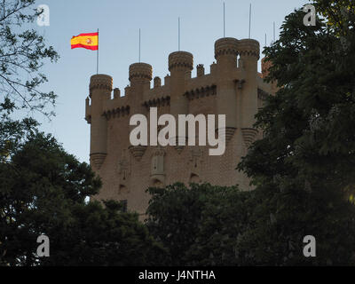 Vue de Ségovie en silhouette château illuminé avec drapeau espagnol au coucher du soleil à travers les arbres, Espagne Banque D'Images