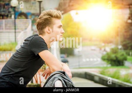 Photo de profil attractive blonde jeune homme en ville Banque D'Images