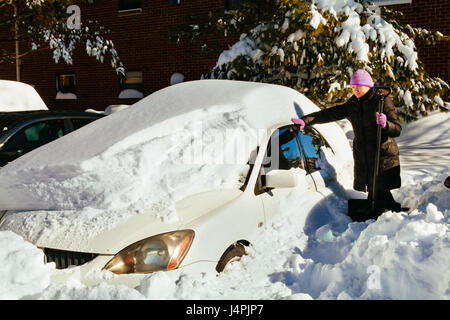 Belle jeune femme enlever la neige de sa voiture belle femme nettoie la neige sur location Banque D'Images