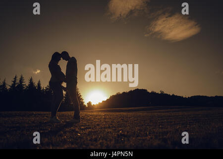 Couple attend un enfant se tenant la main avec amour face à face au coucher du soleil. Banque D'Images