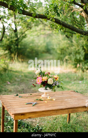 Fleur, l'été et l'arrangement de fleurs fleuriste 24 - concept sur l'été entre les arbres, Belle Glade fresh bouquet de roses blanches et jaunes, les pivoines, les œillets rouges, dans vase blanc sur la table en bois. Banque D'Images