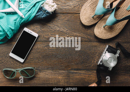 Vue de dessus Accessoires de voyage avec un téléphone mobile, d'une caméra et d'un chiffon lunettes,femme,sandale sur table bois avec copie espace.Travel concept. Banque D'Images