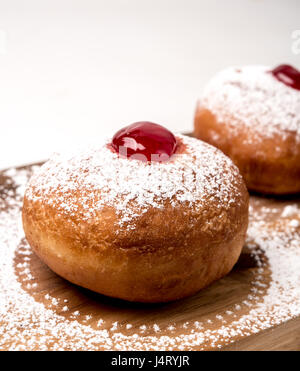 Sufganiyah (sufganiyot) un juif traditionnel Donut mangé pendant Hanoucca avec confiture rouge et le sucre en poudre. Sur fond blanc Banque D'Images