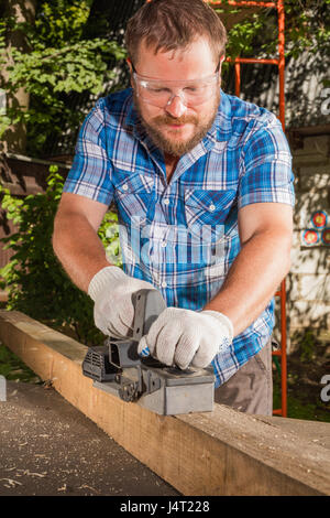 Carpenter broyeuse la planche de bois par l'avion électrique Banque D'Images