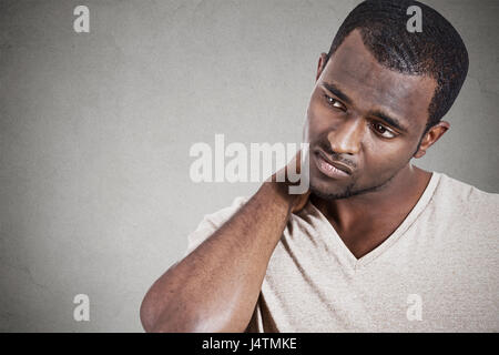 Portrait souligné, malheureux jeune homme séduisant avec vraiment mal la douleur au cou, après de longues heures de travail l'étude de fond de mur gris isolé. Hum négatif Banque D'Images