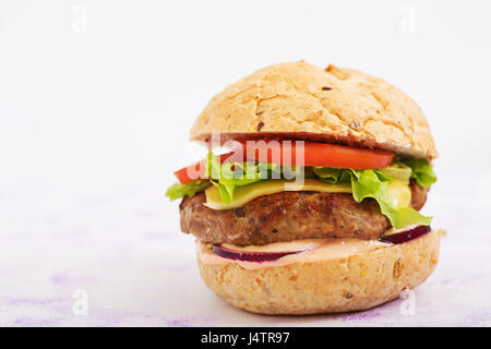 Big sandwich - hamburger avec burger de boeuf juteux, fromage, tomate et oignon rouge sur fond clair et frites. Banque D'Images