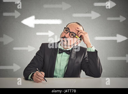 Guy incertain à la recherche à l'aide des flèches. Homme plein de doutes d'hésitation. Closeup portrait perplexe business man pense décider quelque chose de confus incertain isol Banque D'Images