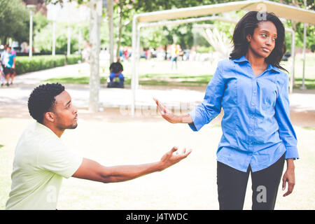 Portrait of young woman showing parler de geste de la main pour homme désespéré dans l'espoir de la convaincre de voir son point de vue. Merci de me ramener. L'extérieur isolé Banque D'Images