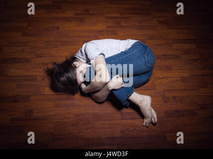 Allongé sur le sol d'une jeune femme solitaire dans une chambre vide Banque D'Images