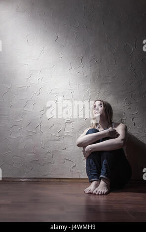 Jeune femme triste assis tout seul sur le sol dans une salle vide Banque D'Images