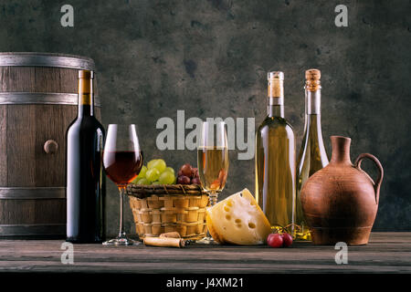 La vie toujours avec des verres de vin de bouteilles et les vignes contre le mur sombre Banque D'Images