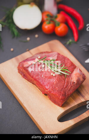 Tartare de boeuf sur une planche à découper, épices et ingrédients pour la cuisson. Banque D'Images