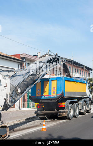 La charge de la machine fraiseuse de asphalte broyé en camion. Banque D'Images