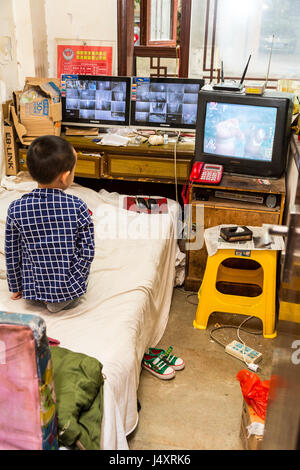 Zhenyuan, Guizhou, en Chine. Jeune garçon regardant la télévision dans sa chambre. Banque D'Images