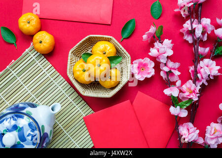 Haut afficher les accessoires le festival du Nouvel an chinois méritoire.orange,bois,feuilles,panier,paquet rouge de prunier,théière sur fond rouge. Banque D'Images