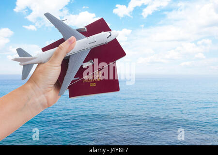 Billet d'avion concept, main tenant les passeports avec le plan d'été sur fond de ciel et mer Banque D'Images