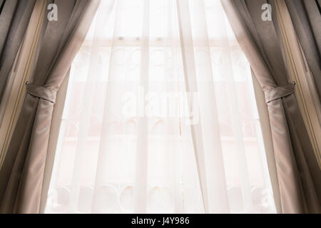 Rideau de soie ouvert de couleur crème sur fenêtre lumineuse couvrant par voir à travers le rideau blanc déménagement en soufflant le vent. Banque D'Images