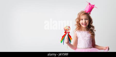 Petite fille en princesse détient un grand couronne décorée en spirale lollipop candy Banque D'Images