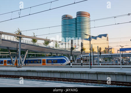 Plates-formes d'Utrecht Centraal Station de chemin de fer avec un train de partir. À l'arrière-plan la Rabobank bâtiment du siège. Utrecht, Pays-Bas. Banque D'Images