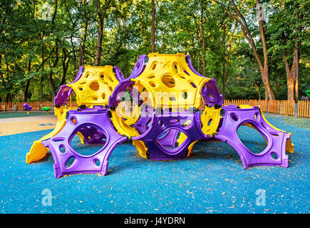 Jeux pour enfants sur les activités de la cour en parc public entouré d'arbres verts à la lumière du soleil le matin. Banque D'Images