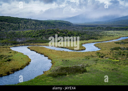 Une rivière serpentines (plein, avec des montagnes en arrière-plan couvert par les nuages Banque D'Images