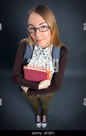 Cute schoolgirl holding book and looking at camera Banque D'Images