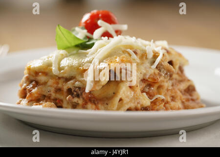 Lasagne maison partie sur plaque blanche sur table en bois Banque D'Images