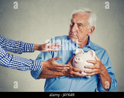 Closeup portrait senior man holding piggy bank grand-père à essayer de protéger son suspect de l'épargne l'vol isolé sur mur gris ba Banque D'Images