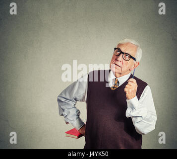 Closeup portrait strict senior teacher holding livre et stylo, jusqu'à la très grave, triste et maussade, gris isolé wall background. L'émotion humaine Banque D'Images