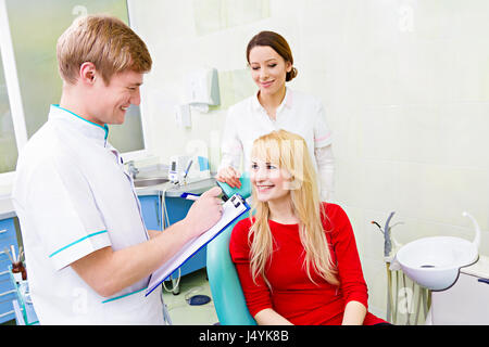 Closeup portrait heureux, female patient, woman sitting in chair, clinique dentaire, de répondre aux questions des professionnels de la santé de sexe masculin, denti Banque D'Images