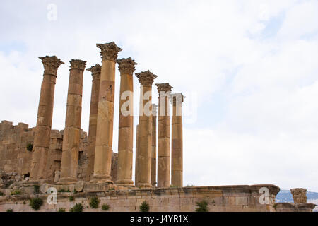 Romain antique Temple d'Artémis avec colonnes et chapiteaux sculptés sur une plate-forme contre un ciel bleu avec des nuages. Photographié à Jerash Jordanie. Banque D'Images