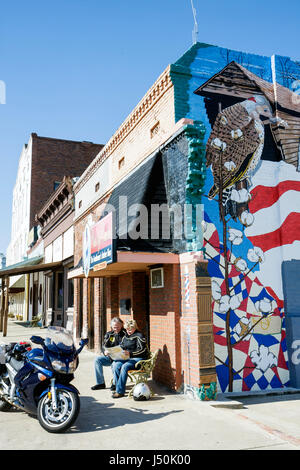 Alabama,Bullock County,Union Springs,Prairie Street,man hommes,femme femmes,couple,moto,banc,lire,barbershop bâtiment,préservation,vers le bas Banque D'Images