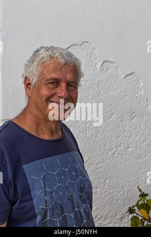 L'île d'Amorgos, Grèce - Octobre 2015 : Portrait of a Smiling man, in front of white rendus mur dans Katapola, Grèce Banque D'Images